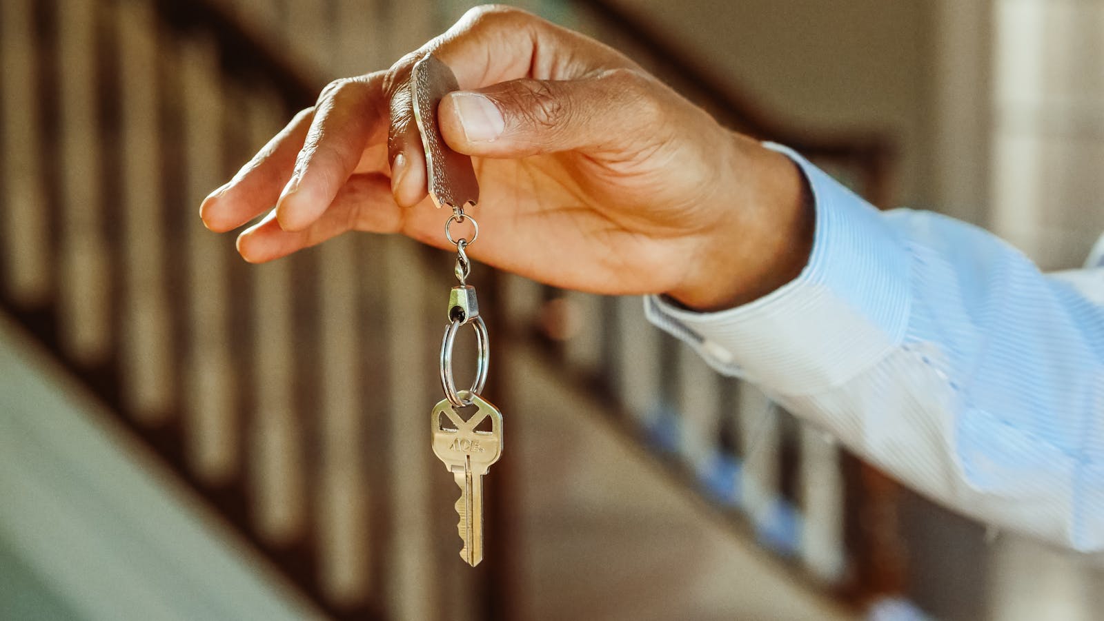 renters, close-up shot of a hand holding a house key, indicating new ownership or rental.